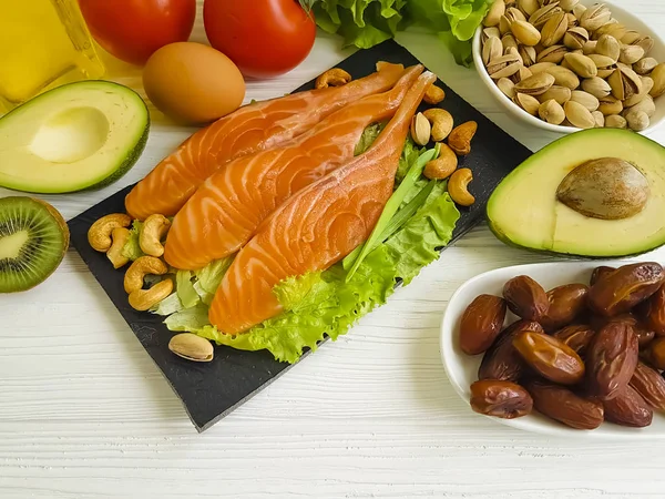 red fish, avocado, nuts on a wooden background