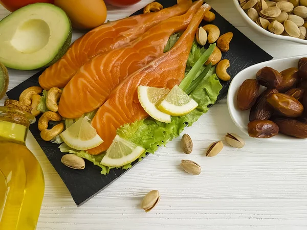 red fish, avocado, nuts on a wooden background