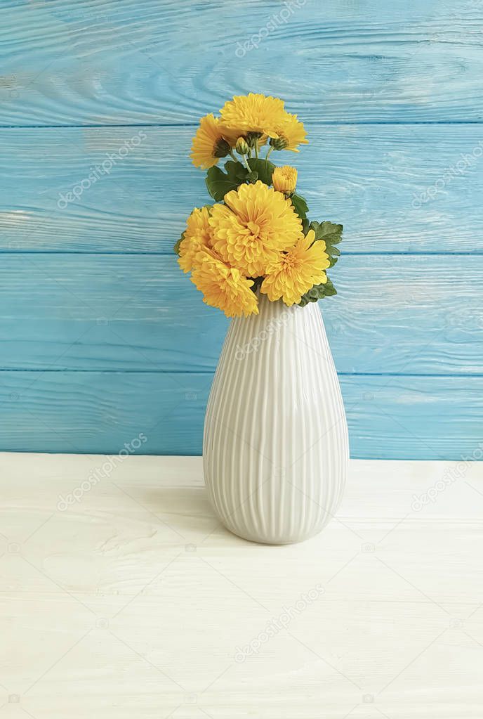 vase of yellow chrysanthemums on a wooden background