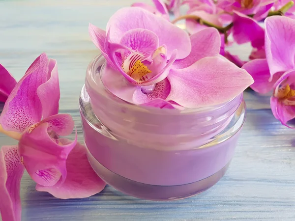 mavi ahşap arka plan üzerinde kozmetik krem orkide çiçek