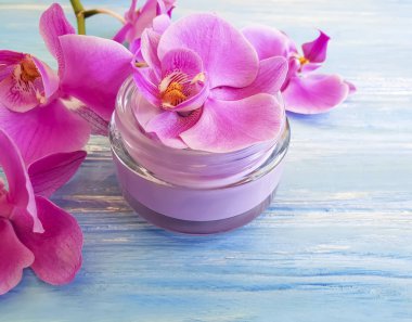 mavi ahşap arka plan üzerinde kozmetik krem orkide çiçek