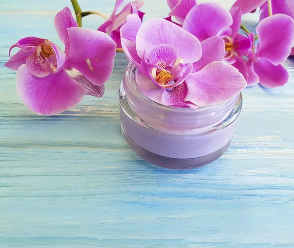 mavi ahşap arka plan üzerinde kozmetik krem orkide çiçek