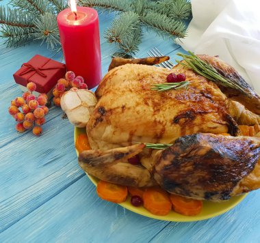 Kızarmış bütün tavuk, mavi ahşap arka plan üzerinde bir Noel ağacının dalını