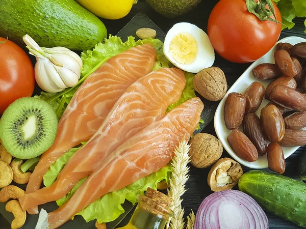 red fish, avocado, nuts on a black wooden background, healthy food