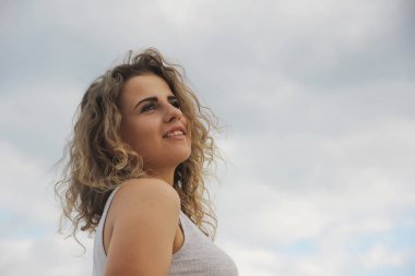 güzel kız mutlu portre kıvırcık saçlı gökyüzü arka plan üzerinde