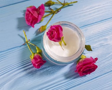 mavi ahşap arka plan üzerinde kozmetik krem gül çiçek