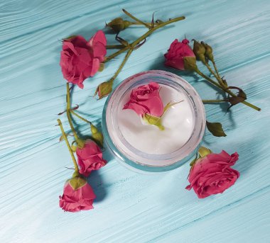 mavi ahşap arka plan üzerinde kozmetik krem gül çiçek
