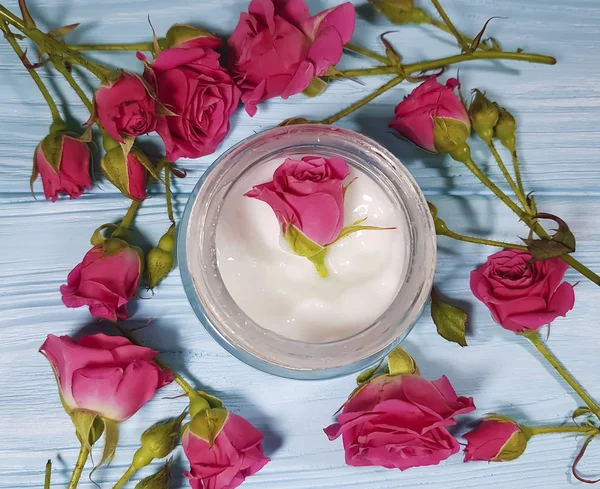 mavi ahşap arka plan üzerinde kozmetik krem gül çiçek