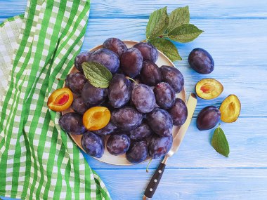 taze organik Erik bir plaka, mavi ahşap arka plan, havlu, bıçak