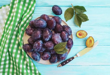 taze organik Erik bir plaka, mavi ahşap arka plan, havlu, bıçak