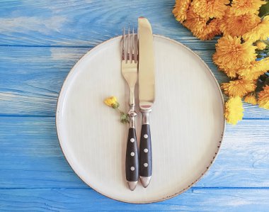 çatal, plaka, mavi ahşap zemin üzerine sarı kasımpatı bıçakla