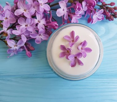 mavi ahşap arka plan üzerinde kozmetik krem, Lila çiçek