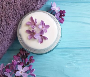 mavi ahşap arka plan üzerinde kozmetik krem, Lila çiçek