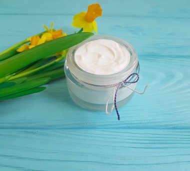 mavi ahşap arka plan üzerinde kozmetik krem nergis çiçek