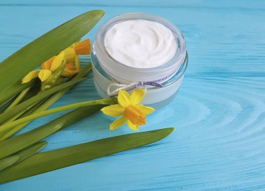 mavi ahşap arka plan üzerinde kozmetik krem nergis çiçek