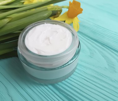 mavi ahşap arka plan üzerinde kozmetik krem nergis çiçek