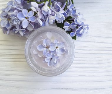 Beyaz ahşap zemin üzerinde kozmetik krem, Lila çiçek