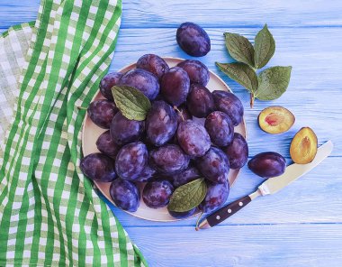 mavi ahşap renkli bir tabağa olgun organik Erik