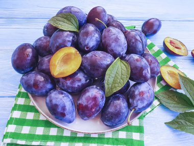 mavi ahşap renkli bir tabağa olgun organik Erik