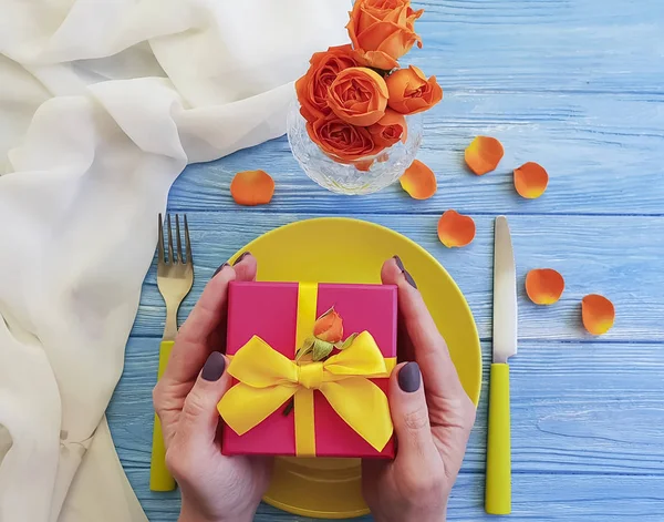 female hands plate, fork, knife gift box flower rose on wooden