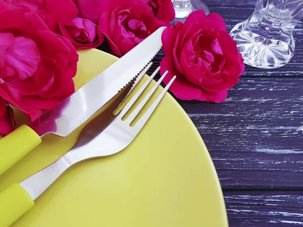 fork, knife, plate rose flower on wooden background