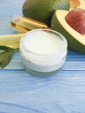 mavi ahşap arka plan üzerinde organik kozmetik taze avokado yağı, krem