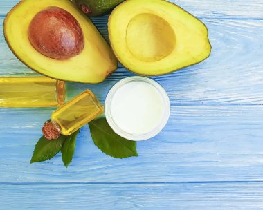 mavi ahşap arka plan üzerinde organik kozmetik taze avokado yağı, krem