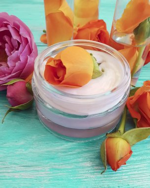 bir mavi ahşap arka plan üzerinde kozmetik krem taze turuncu gül