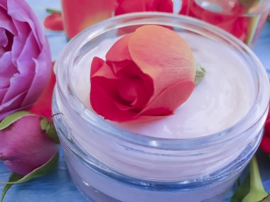 bir mavi ahşap arka plan üzerinde kozmetik krem taze turuncu gül