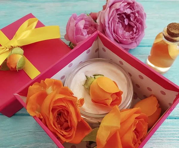extract, essence gift box cosmetic cream fresh orange rose on a blue wooden background