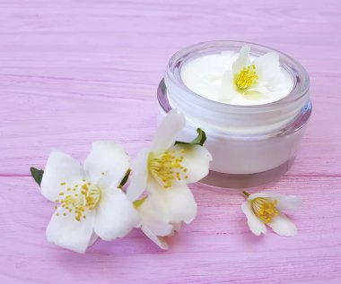 pembe ahşap arka plan üzerinde kozmetik krem Yasemin çiçeği