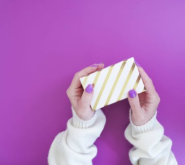 renkli bir arka plan üzerinde bir hediye kutusu ile manikür eller tutun