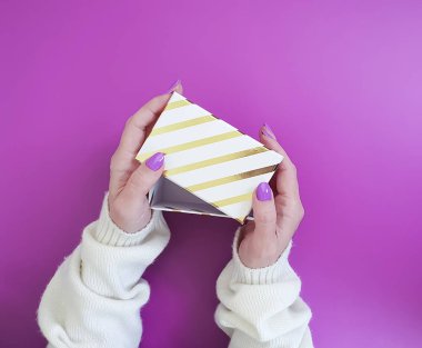 renkli bir arka plan üzerinde bir hediye kutusu ile manikür eller tutun