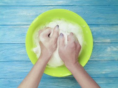 Erkek bir havza ahşap arka plan üzerinde çamaşır giysilerle eller