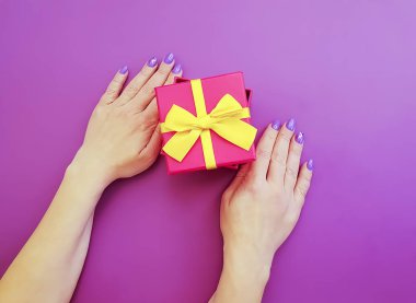 Kadınların elleri bir hediye kutusu renkli bir arka plan üzerinde tutun