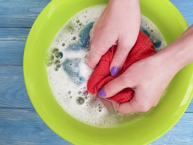 ahşap arka plan üzerinde bir havzasında giysi yıkama eller