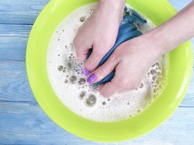 ahşap arka plan üzerinde bir havzasında giysi yıkama eller