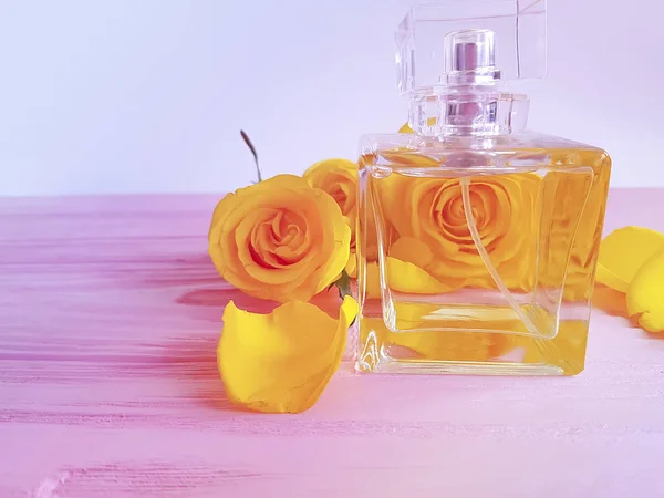 花の黄色の木製の背景にバラの香水 — ストック写真
