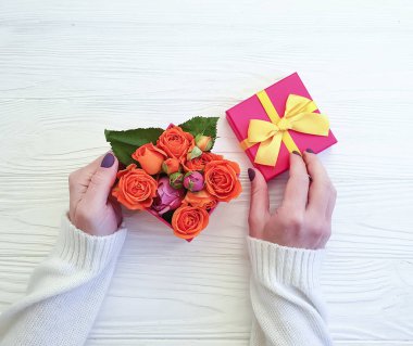 eller hediye kutusu, gül çiçek ahşap arka plan üzerinde tutun.