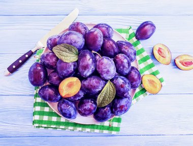 taze organik Erik plaka üzerinde mavi bir ahşap arka plan