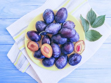 taze organik Erik plaka üzerinde mavi bir ahşap arka plan