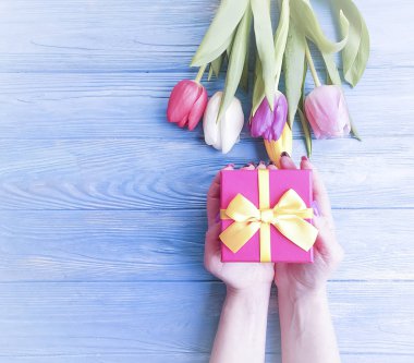bir hediye kutusu, Lale mavi ahşap arka plan üzerinde bir buket tutan eller