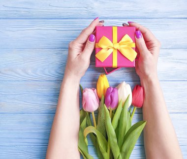 bir hediye kutusu, Lale mavi ahşap arka plan üzerinde bir buket tutan eller