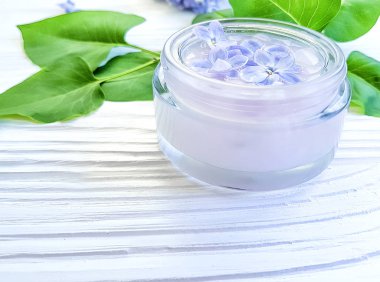 Beyaz ahşap zemin üzerinde kozmetik krem çiçek leylak