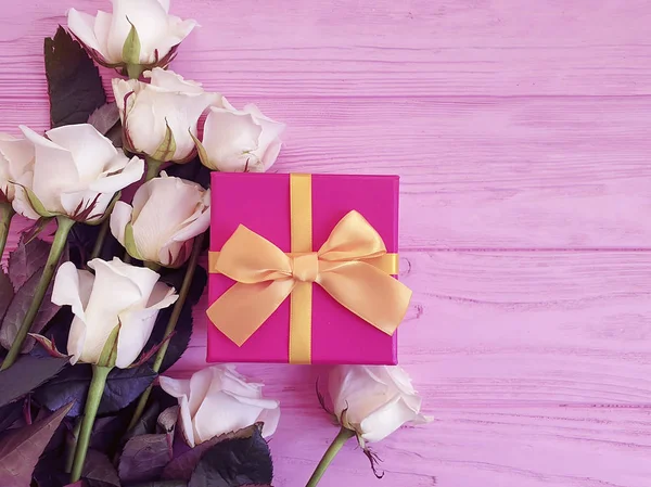 bouquet of white roses, gift box on a pink wooden background