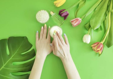 kadın elleri, manikür, kozmetik krem, lale renkli bir arka plan üzerinde