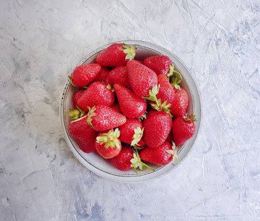 gri beton arka plan üzerinde bir tabak ta taze çilek