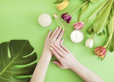kadın elleri manikür, renkli bir arka plan üzerinde krem kozmetik lale
