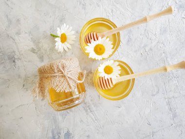 fresh honey, chamomile flower on gray concrete background