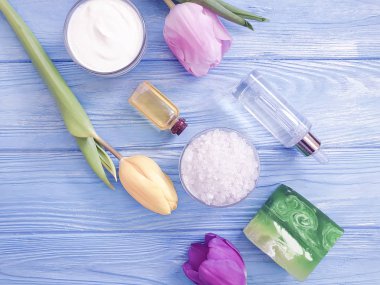ahşap arka planda kozmetik krem, sabun, tuz, lale çiçeği